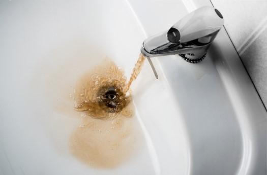 Dirty brown water running into a sink