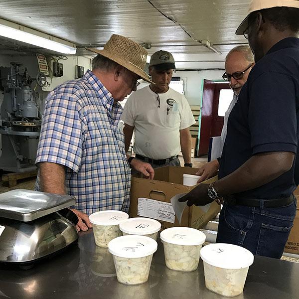 Image of HPP processed crabmeat being inspected and prepared for shipment