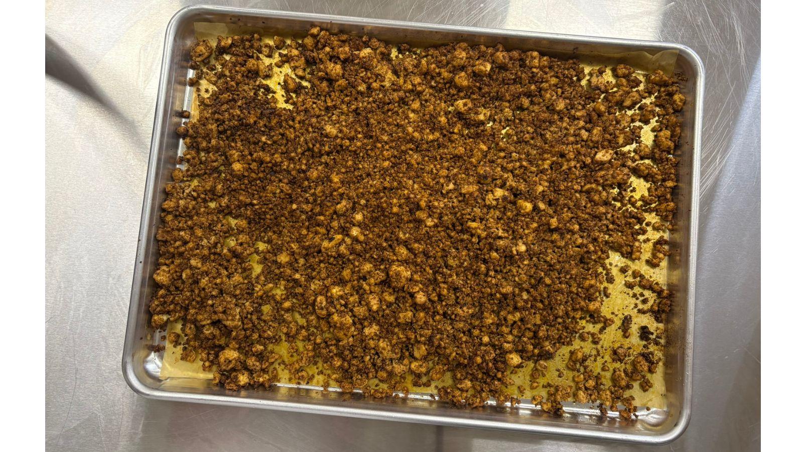Chorizo-Style roasted tofu crumbled across a metal sheet pan on a metal surface