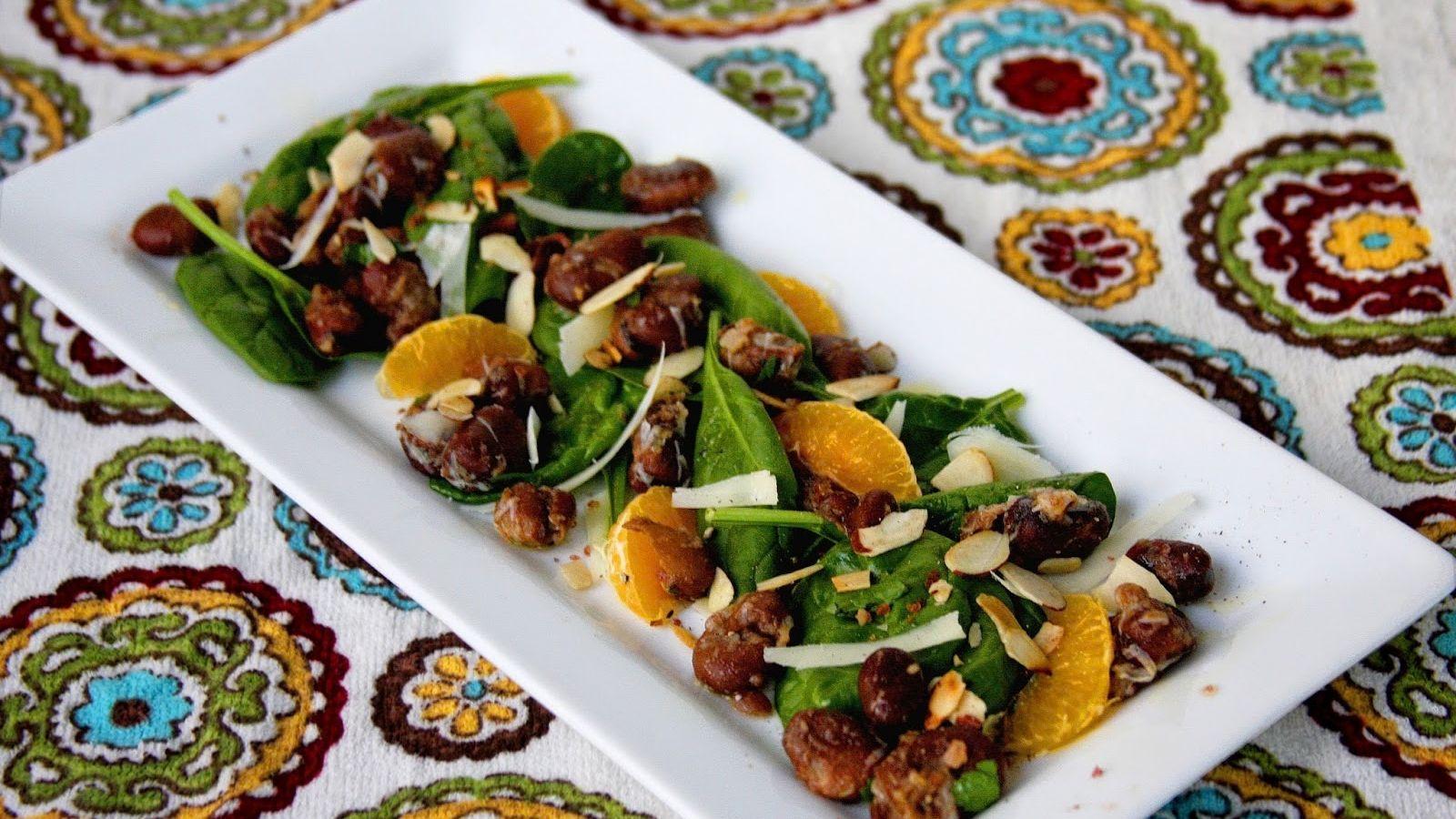 Fava bean salad with clementines on a white rectangular plate on a tablecloth with decorative circles