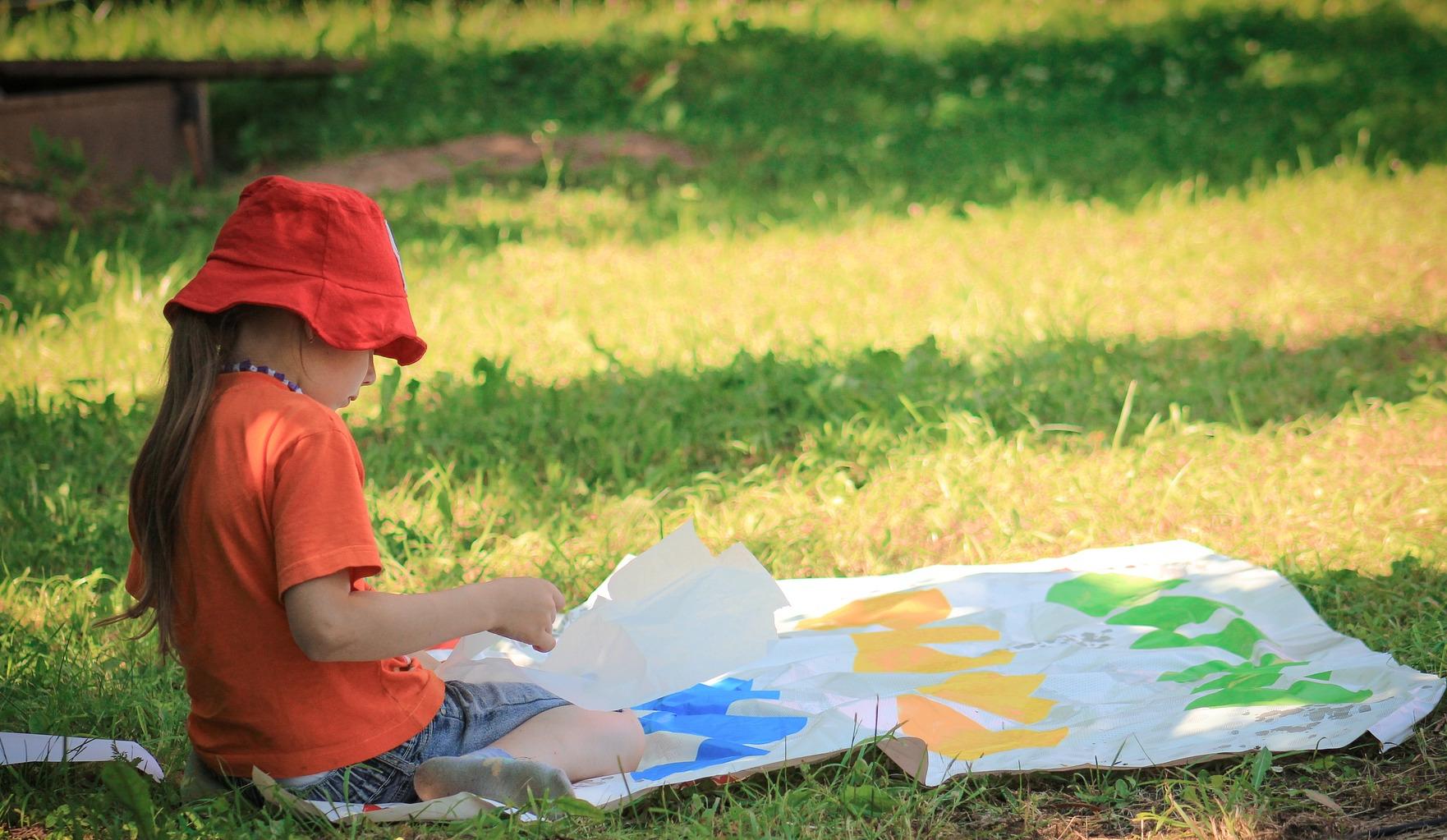 a girl sitting on the ground in a lawn with weeds in the shade