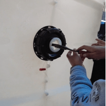 A person using an adjustable wrench to tighten the cap on the base of the grow bed.