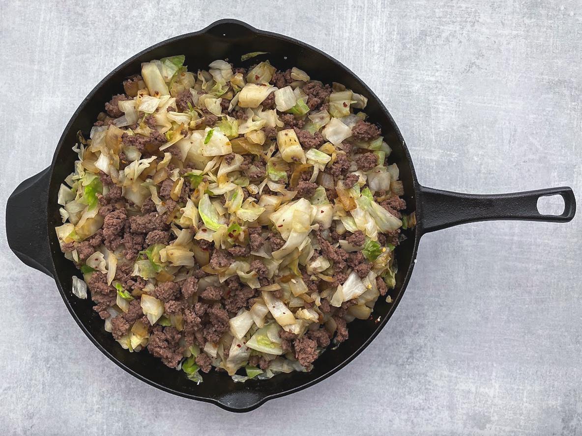 Ground beef and cabbage cooked in a cast iron skillet.