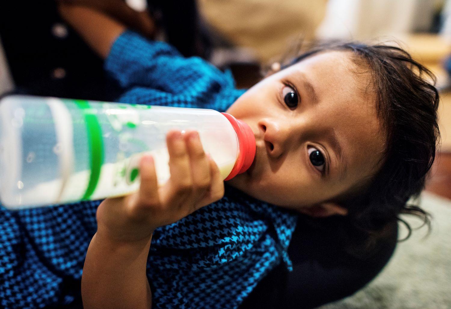Child drinking formula in a bottle