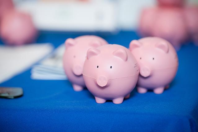 Three pink piggy banks on a blue tablecloth
