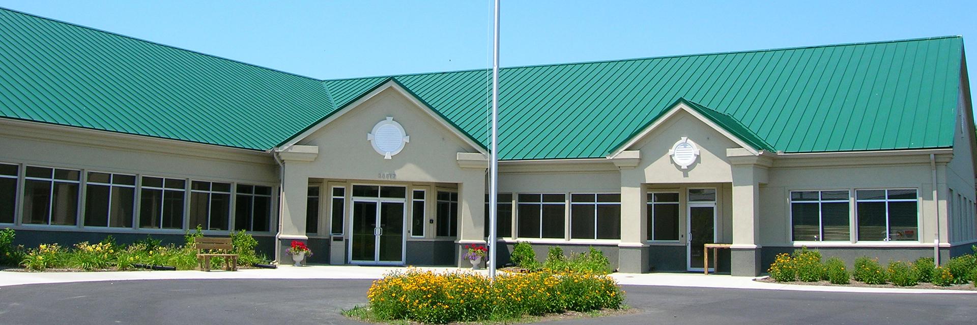 Talbot county tan office with green roof and yellow flowers surrounding a flag pole