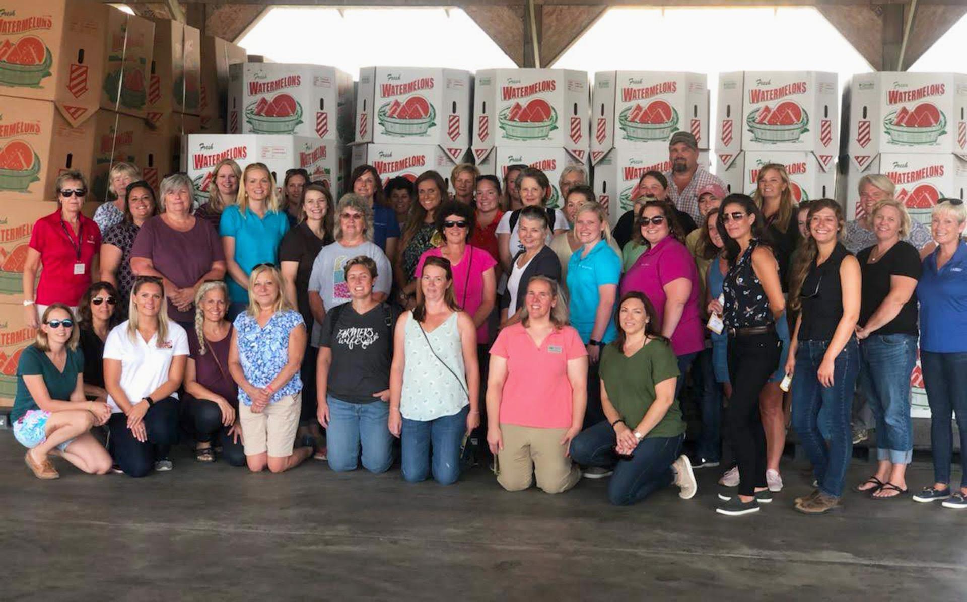 women in agriculture group standing in front of watermelon boxes on a farm tour
