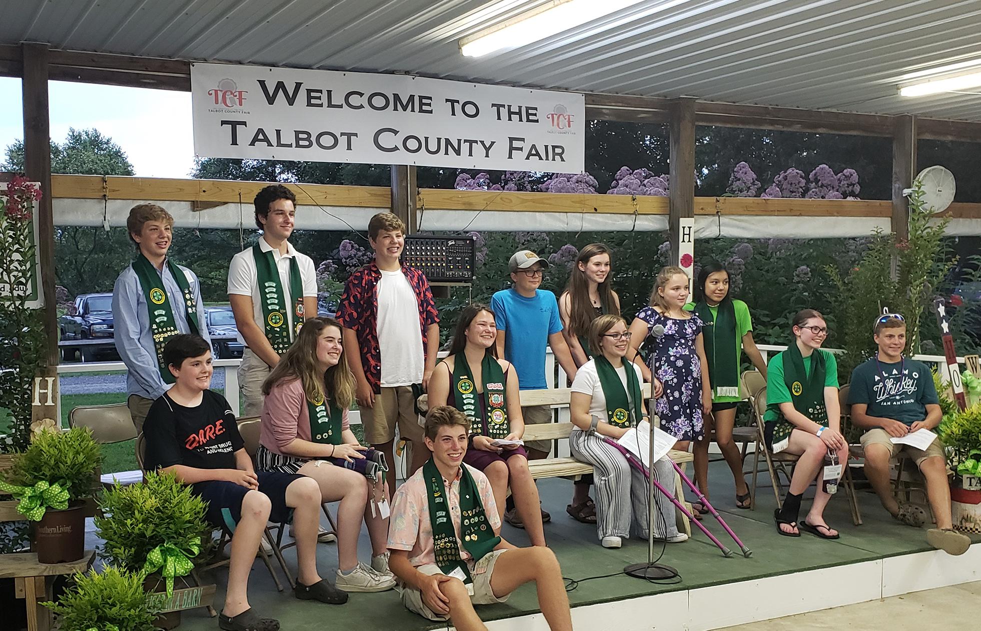 The Talbot 4-H Ambassadors sit in front of the Welcome to the Talbot County Fair sign