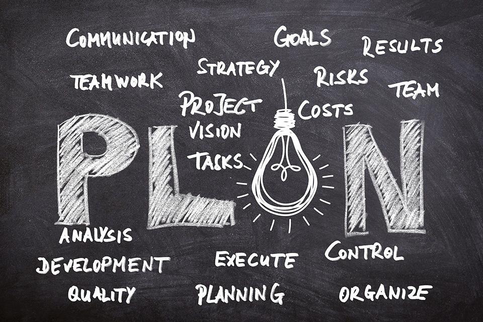 Business plan chalkboard with text: communication, teamwork, strategy, goals, results, risks, team, costs, project, vision, tasks, analysis, development, quality, execute, planning, control, organize, and plan.
