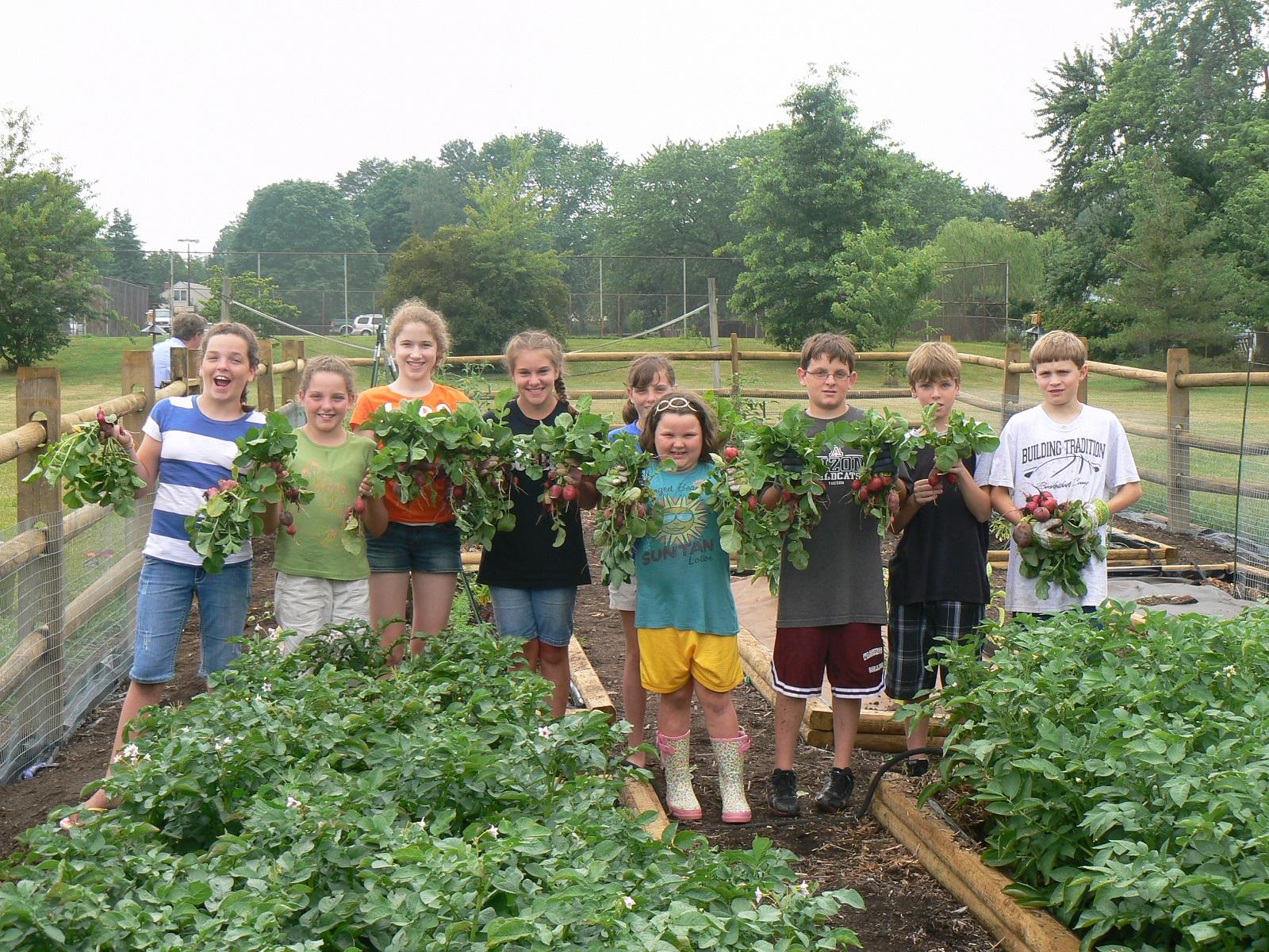 children proudly showing harvested crops from their garden