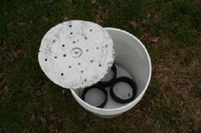 Third step pf self-watering container with black feet made of cut pipe at the bottom