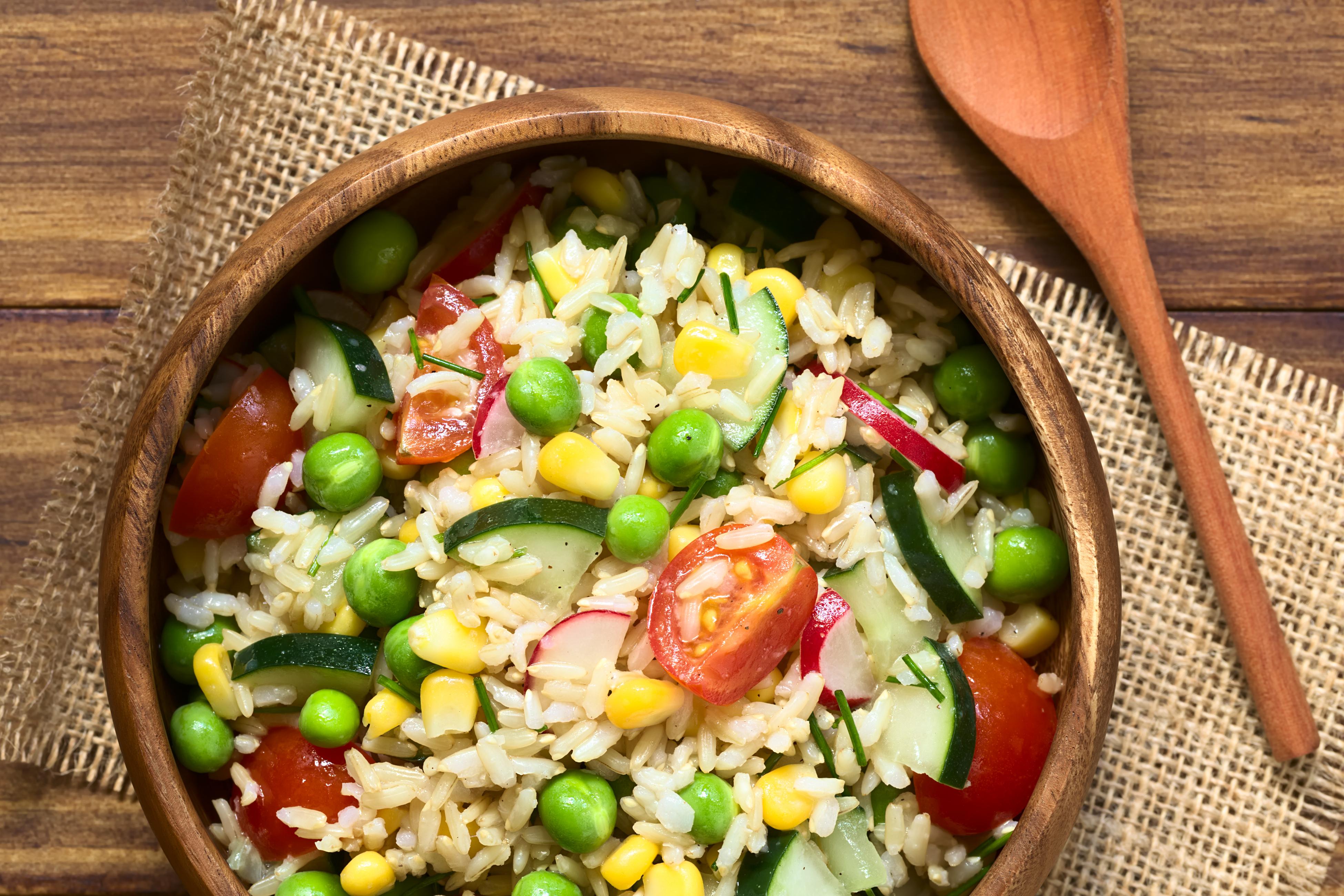 Rice dish with cucumbers, peas, corn, and tomatoes in a wooden bowl (Shutterstock -- LW rights)