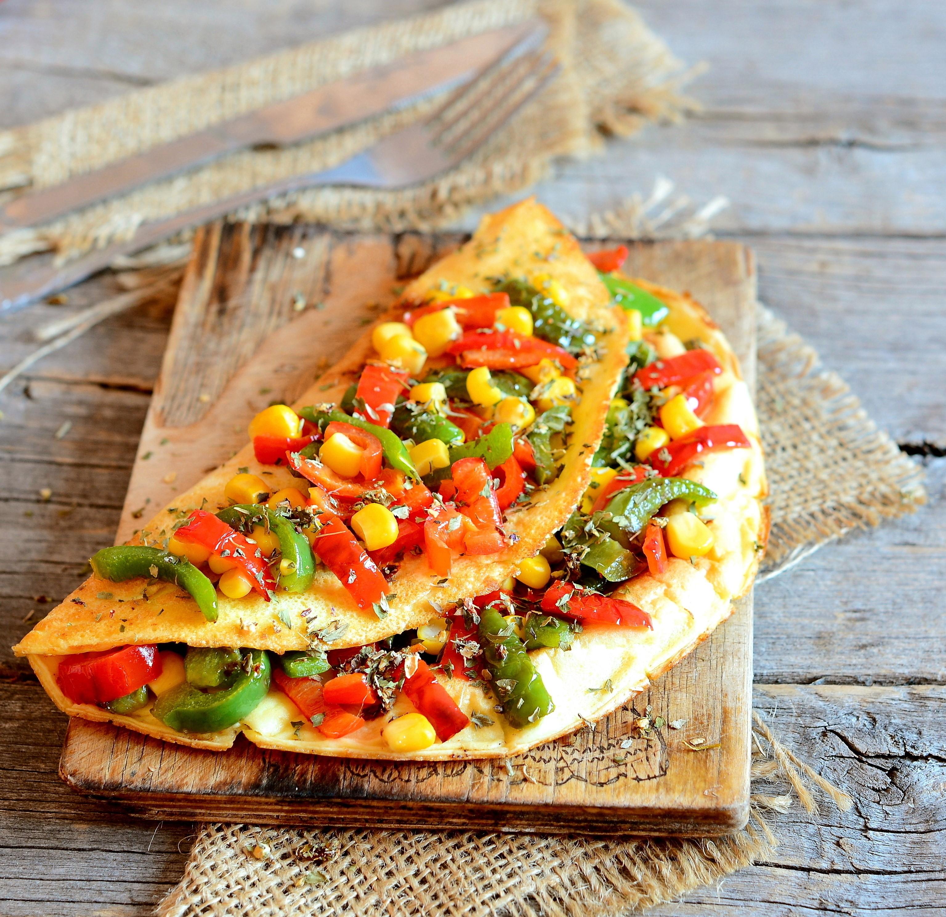 Omelet topped with canned vegetables on a wooden background.