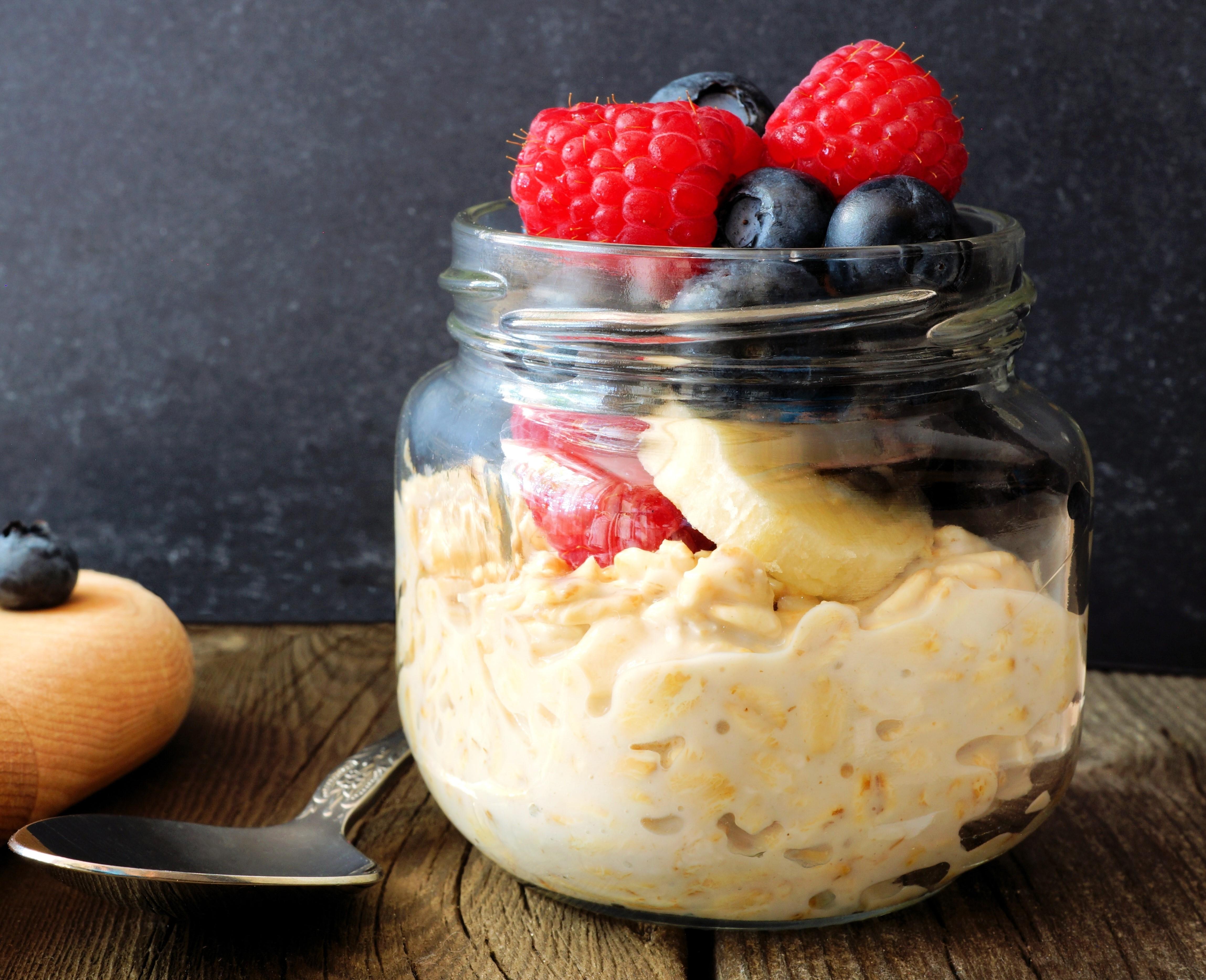 Oats soaked in milk in a small glass jar and topped with blueberries, raspberries, and banana.