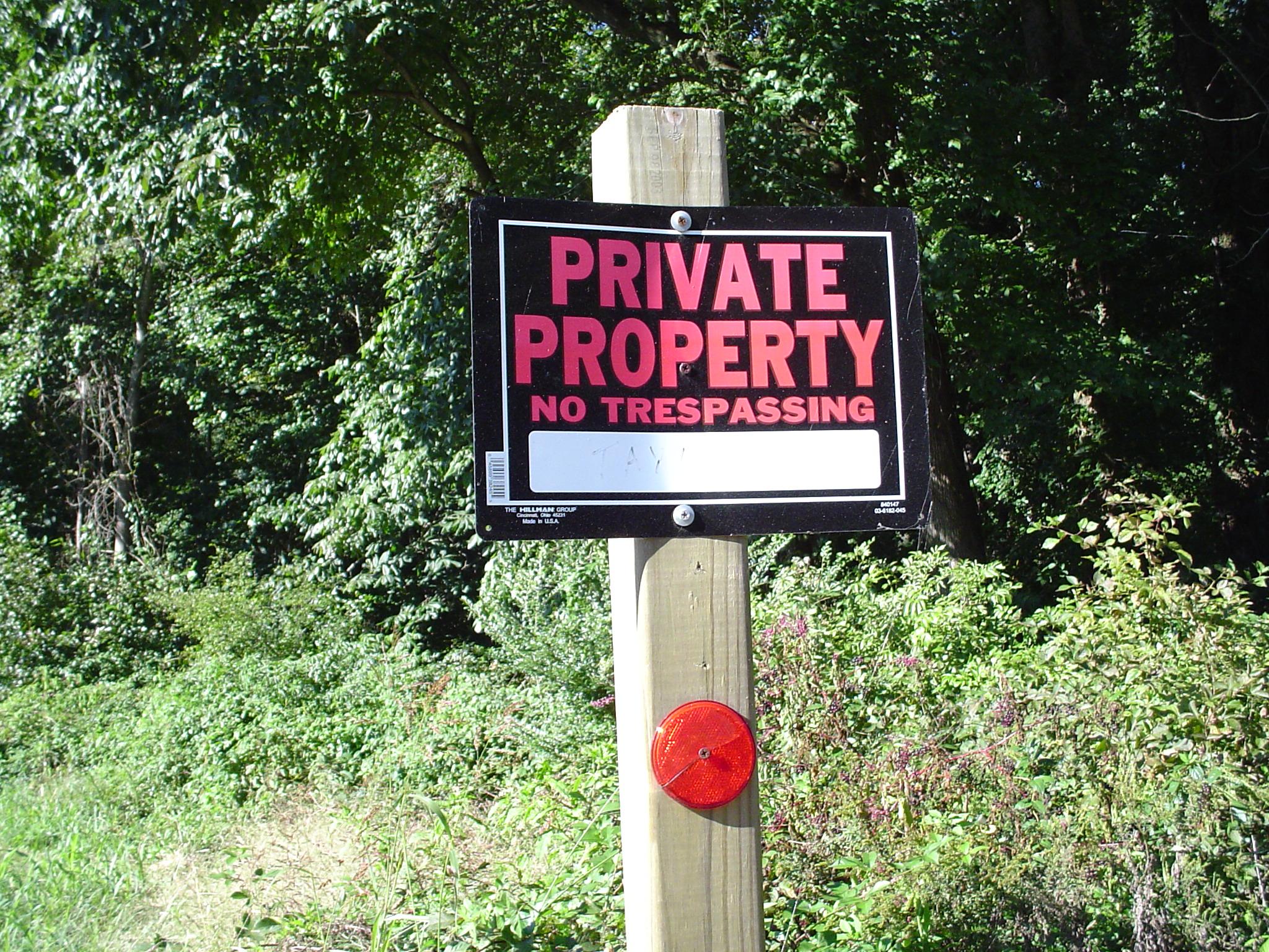 Private Property, No Trespassing sign posted on wooden post
