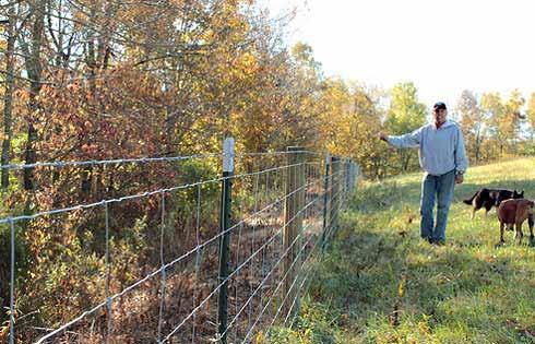 Man standing by a wire fence, Photo: USDA blog at http://blogs.usda.gov/2013/01/24/retiree-improves-and-diversifieskentucky- farm-for-future-generat ions/