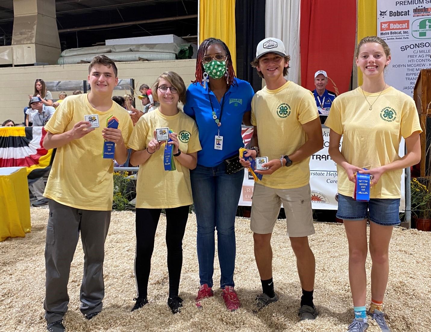 4-H members and 4-h leader hold winning ribbons