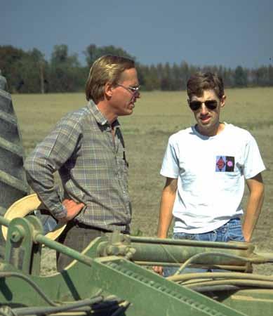 Two men talking next to farm equipment