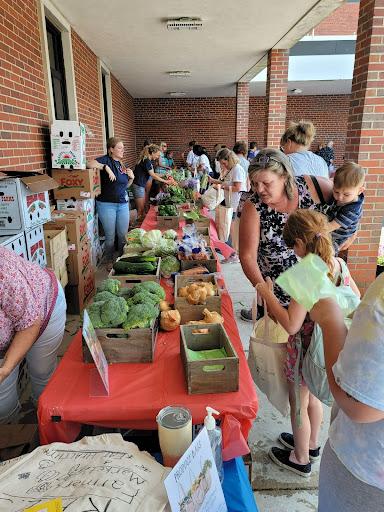Families picking produce from an outdoor farmers market.
