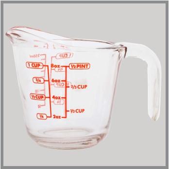 Pint size glass liquid measuring cup with a handle and measurements in Ounces and Cups as well as Metric milliliters.