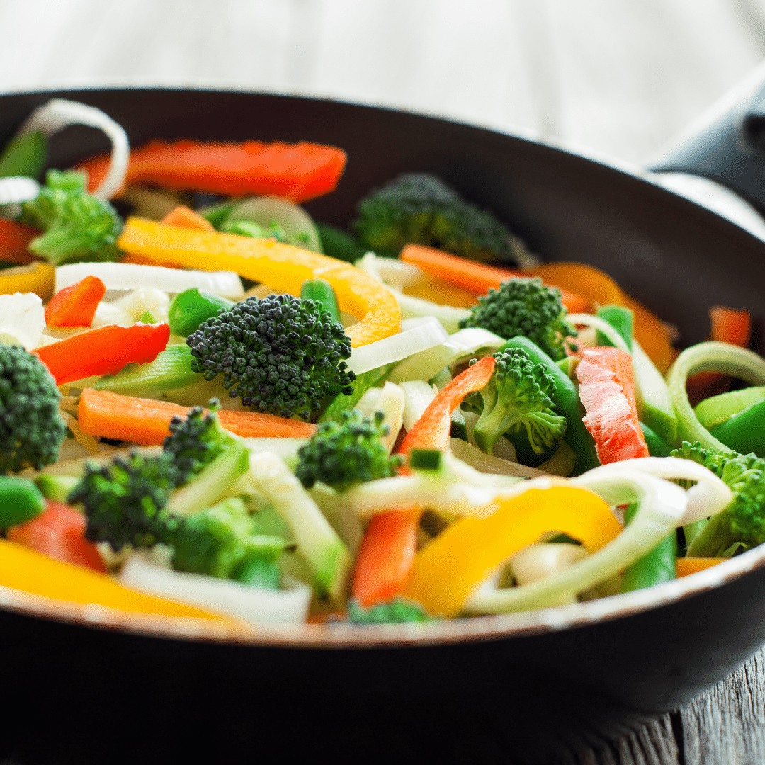 A variety of colorful vegetables in a pan cooking.