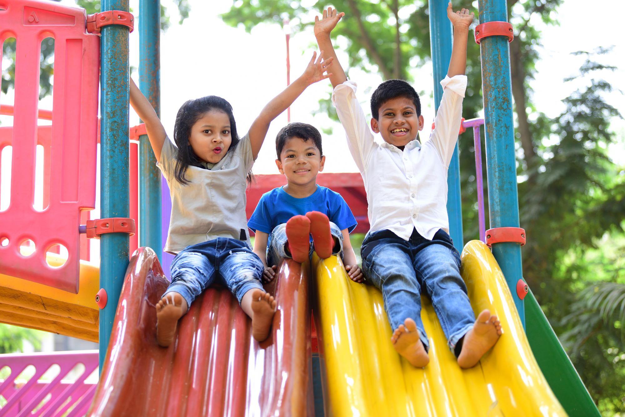 three children sliding down a slide.