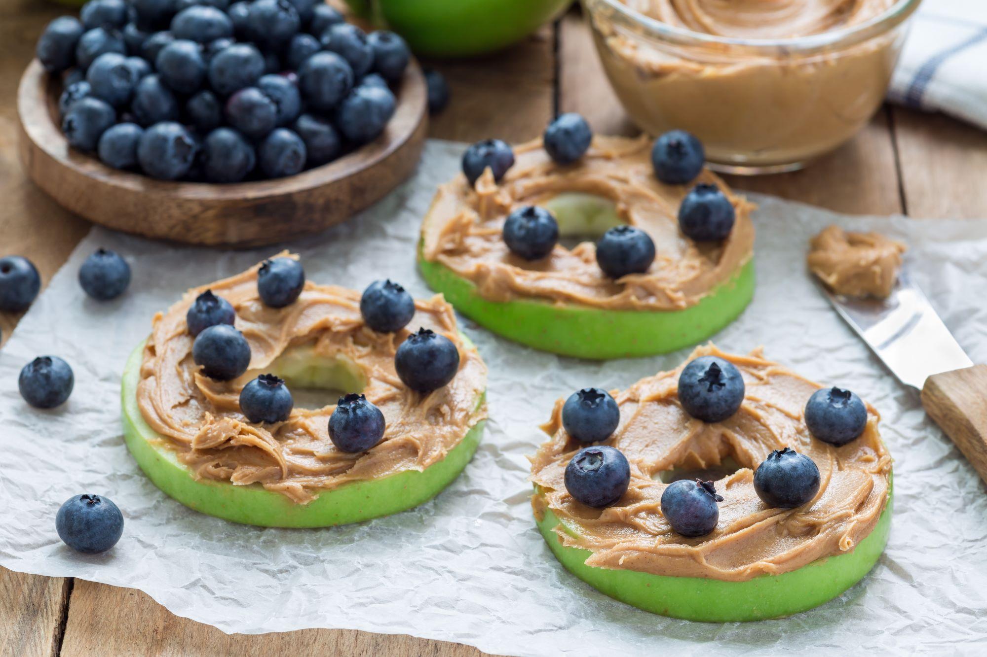 Green apples sliced and topped with peanut butter and blueberries.
