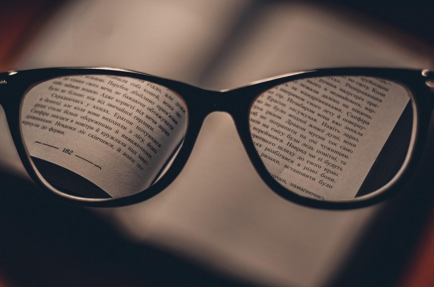 A pair of glasses magnifying the words on a book.
