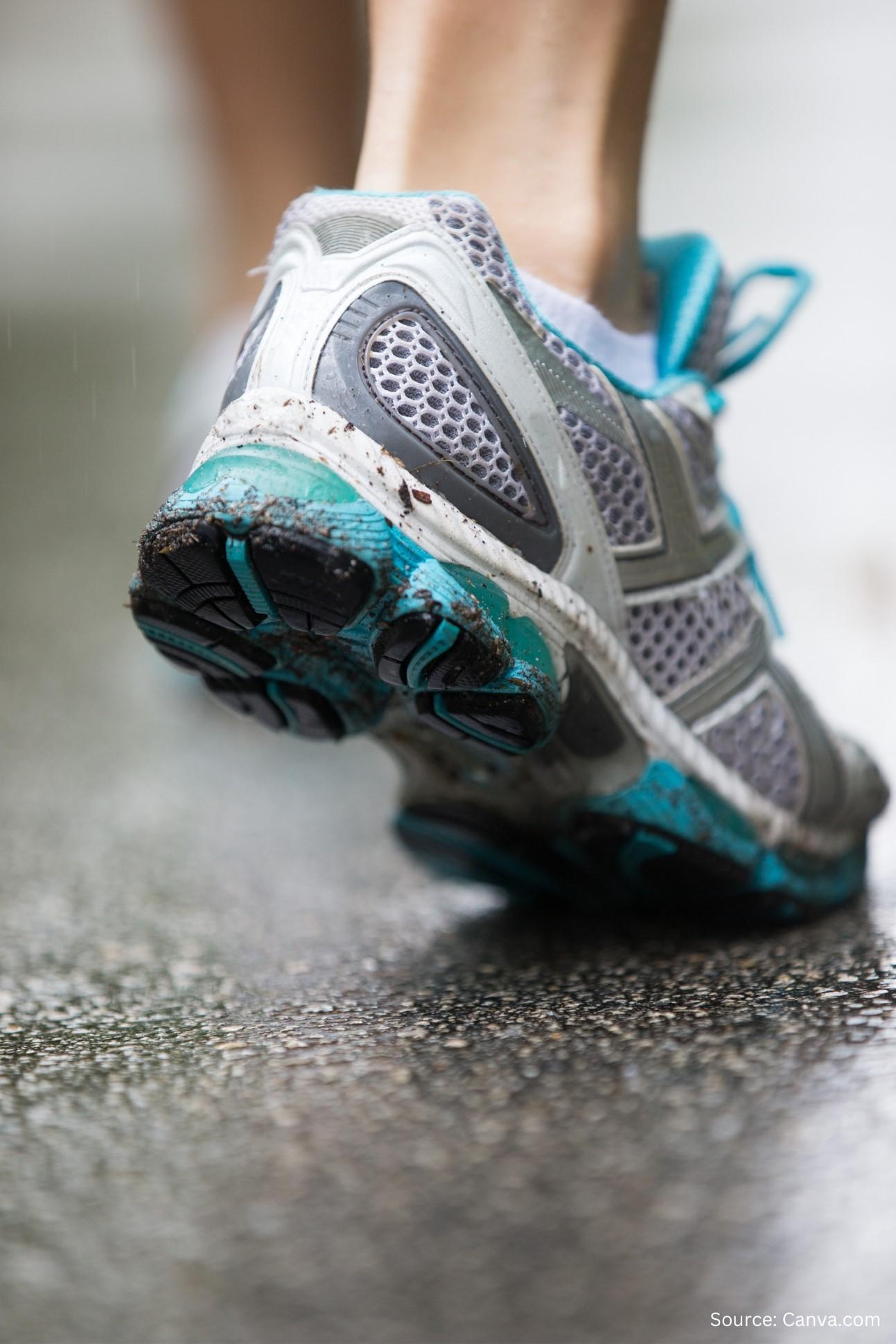 A human leg is wearing a grey and teal running sneaker.