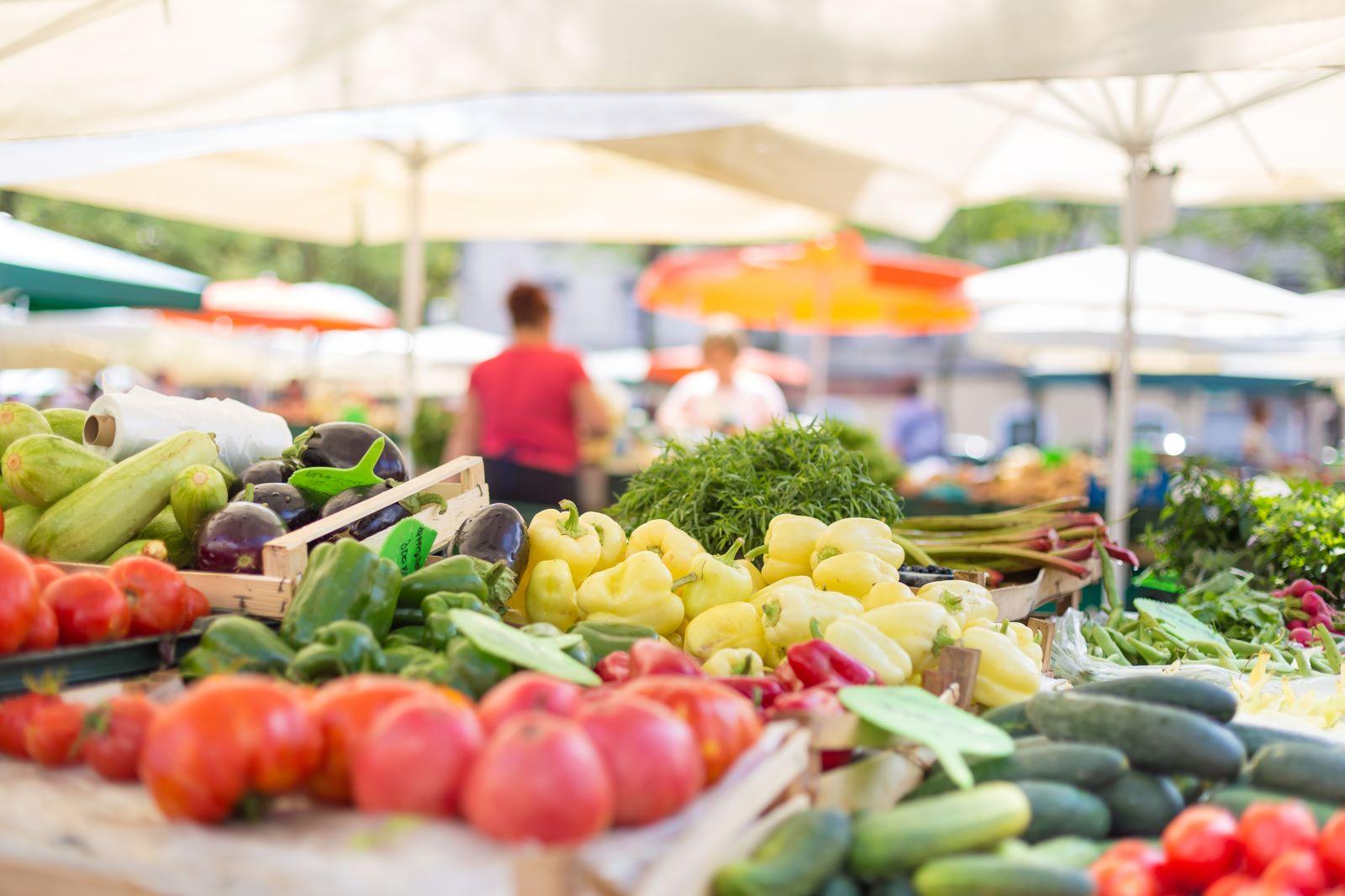 A spring farmers market with a variety of fruits and vegetables under a white tent.