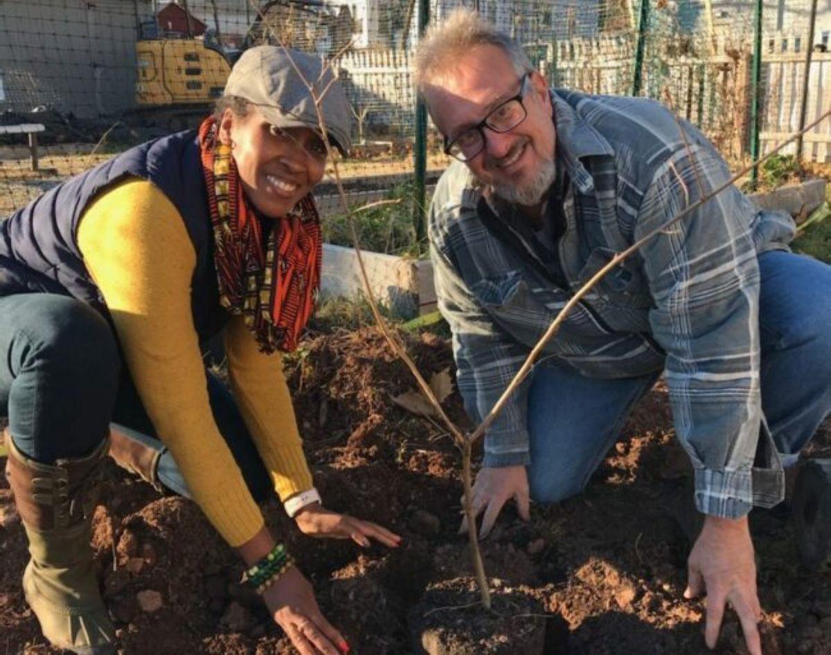 John Evangelista and volunteer planting a sapling
