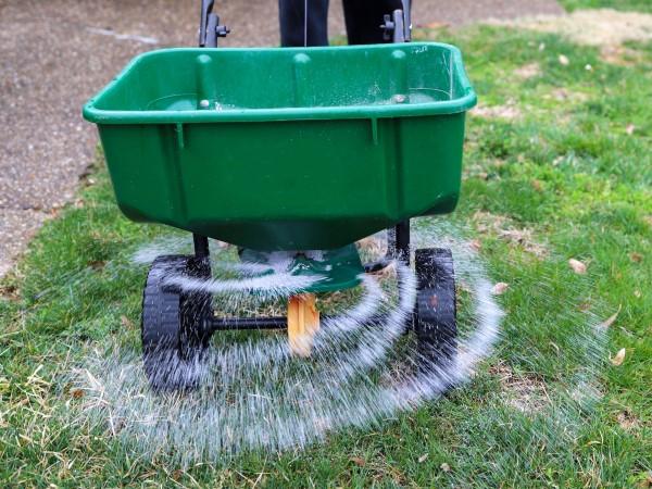 Wheeled walk-behind lawn spreader consisting of a basin that empties onto a rotating disc that flings the material onto the lawn.