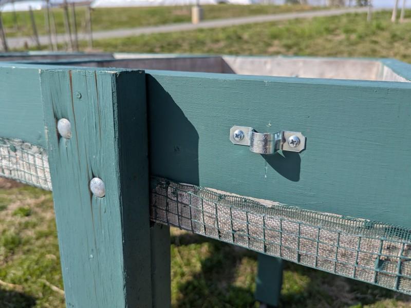 Close-up of the outside of a Salad Table frame, showing two bolts attaching the leg and a bracket used to anchor a piece of pipe.