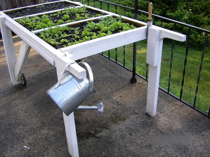 A painted Salad Table with wheels on one pair of legs and handles built into the other pair of legs.