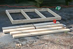 Wooden boards laid on the ground in a group of different lengths, ready for assembly and into a finished table frame.