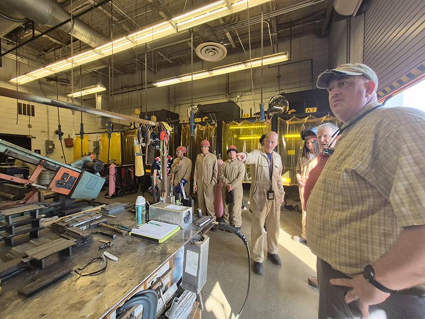 Frank Holiday shows North Point High School's welding facilities to UME faculty