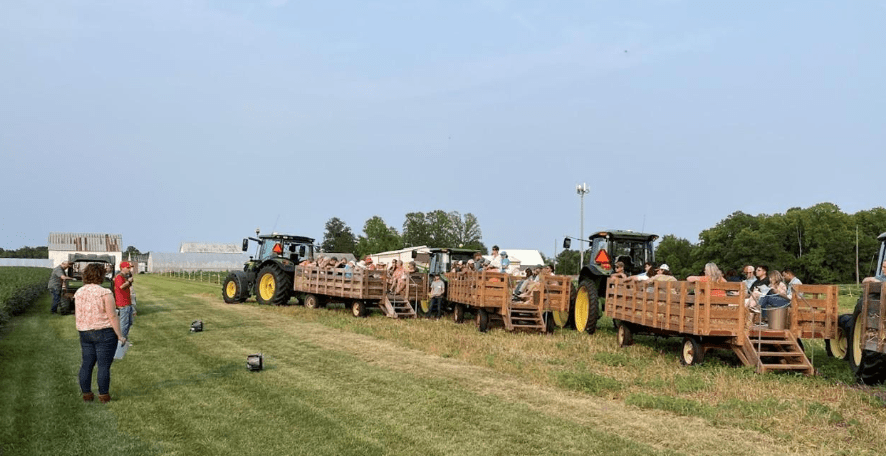 People speaking on Farm to tractors filled with people on a tour