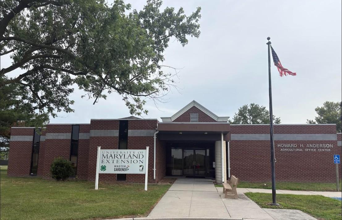 Somerset County Extension Office: brick building with a flag pole and bench to the right of the entrance, and white UME sign to the left.