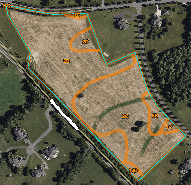 Aerial photograph showing a large field outlined with orange boundary lines. The sections are labeled with numbers such as 1B, 2B, 2C, 5B, and 1C; these are the different soil types in the field. Surrounding the field are residential houses, roads, and trees.