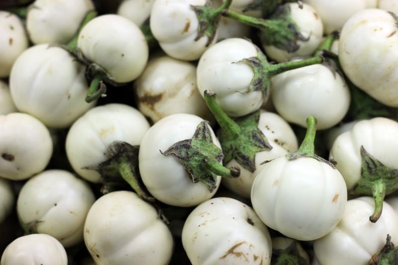 A pile of harvested small, rounded, white-skinned fruits with green stems.