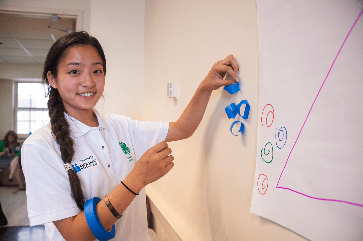 A girl looking in the camera and smiling while doing 4-H Youth Club activity 