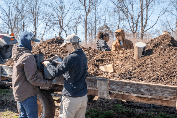 volunteers working together to load compost into a trailer