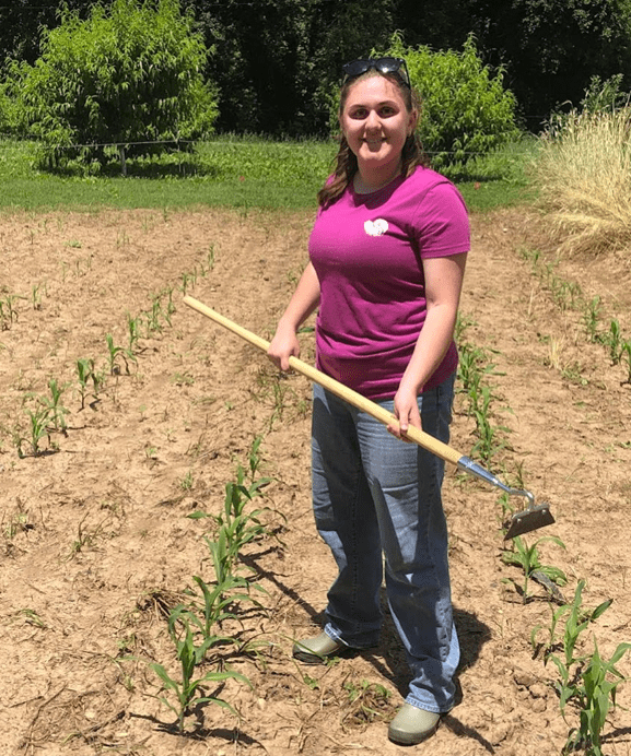 Abi Anderson in field with a hoe in her hand