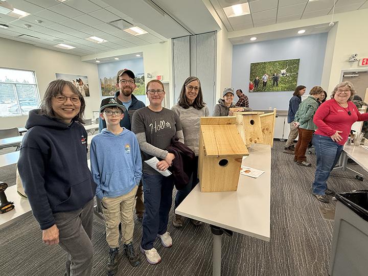 Members of the Howard County Bird Club pose alongside a raptor box they built during a workshop at CMREC