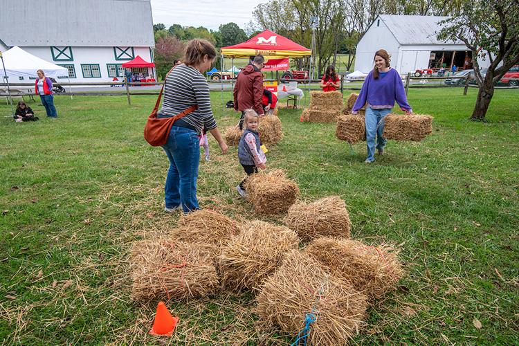 A family watches a hay bale carrying competition at the Frederick County Ag Olympics